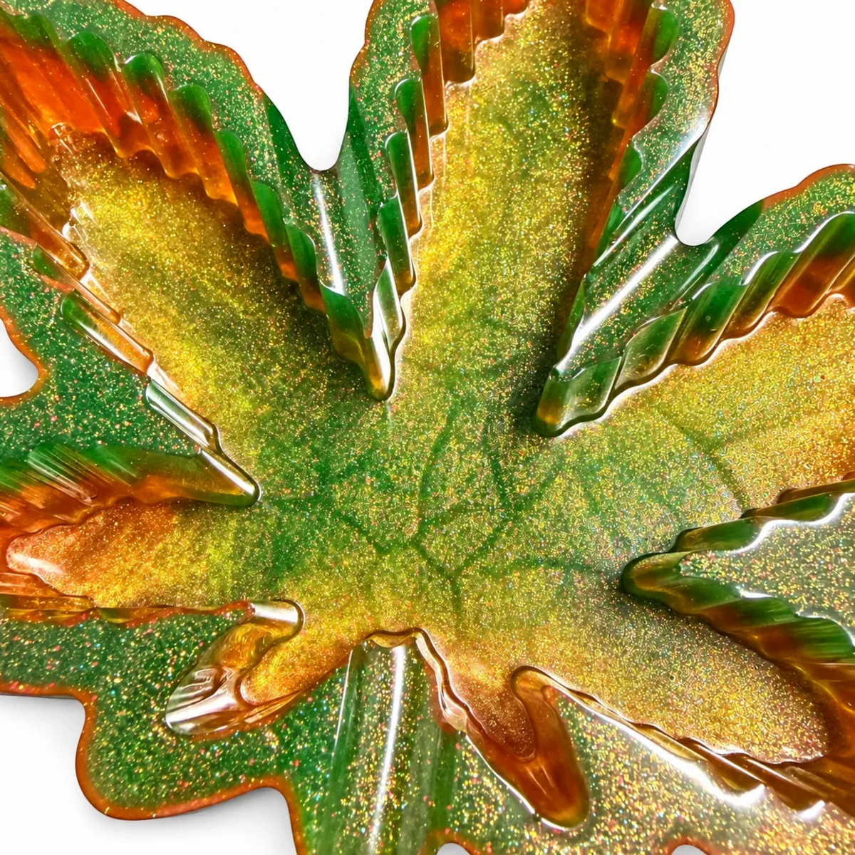 White Ashes Smoke Shop cannabis leaf shaped resin rolling tray in shimmering green and gold with a high-gloss finish.